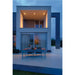 Modern two-story house exterior with outdoor patio, wood table, metal chairs, and recessed lighting.