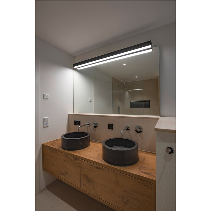 Bathroom with two dark stone vessel sinks on a wood vanity, under a large mirror with integrated lighting.