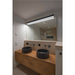 Bathroom with two dark stone vessel sinks on a wood vanity, under a large mirror with integrated lighting.