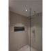 Modern shower with glass door, recessed black niche, and beige stone tile.
