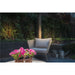 Wicker outdoor chair with gray cushion, pink petunias in basket, and copper finish garden lights.