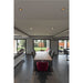 Modern dining room with wood table, gray leather chairs, and red velvet accent chair on dark tile floor.