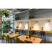 Modern cafe interior with light wood tables, yellow and burgundy chairs, and wall-mounted black sconces.