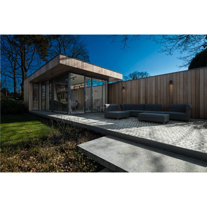 Modern outdoor space with wood siding, gray wicker furniture, and stone patio.
