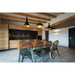 Dining room with wood table, smoke-tinted acrylic chairs, and black pendant lights with gold interiors.