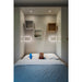 Built-in bed nook with gray cabinets, floating wood and white shelves, and wall-mounted white sconces.