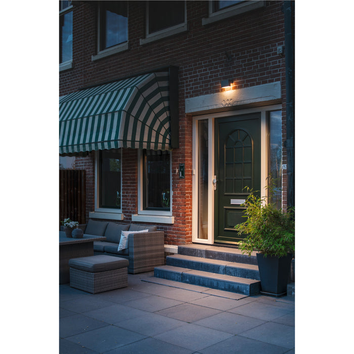 Dark bronze outdoor LED wall light fixture mounted above a green front door.