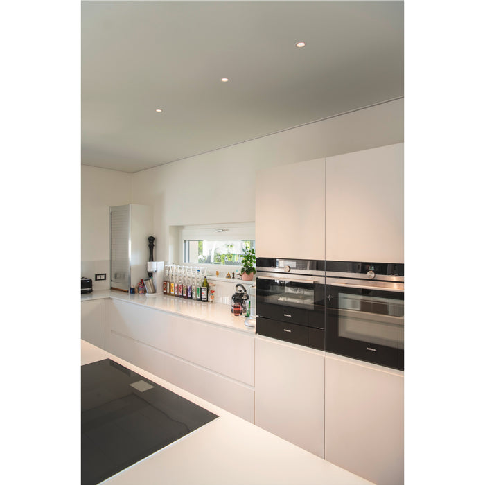Modern kitchen with white cabinets, black Siemens ovens, and recessed ceiling lights.
