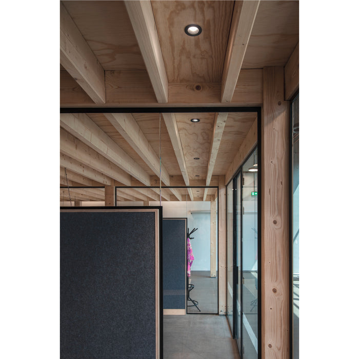 Modern office interior with exposed wood beams, black framed glass walls, and gray acoustic panels.