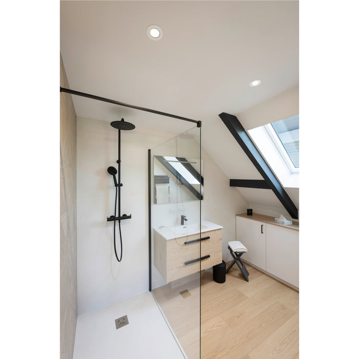 Modern bathroom with black shower fixture, light wood vanity, and glass shower screen.