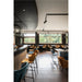 Restaurant interior with velvet upholstered chairs in blue and gold, black metal frames, and wood bar.