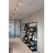 Black metal shelving unit with various decorative urns and flower arrangements in a hallway.