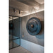 Hanging metal gong, dark blue patina finish, suspended by rope.