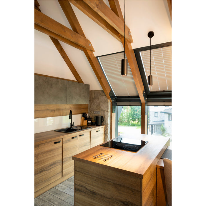 Modern kitchen with wood cabinets, black sink and faucet, stone wall, and black pendant lights.