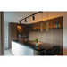 Modern kitchen with black track lighting, gold pendant lights, dark wood cabinets, and a white island with a black countertop.