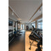 Home gym with black metal weight rack, dumbbells, and cardio machines on rubber and wood floors.