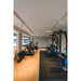 Home gym with black metal power rack, weights, treadmill, and wood floor.
