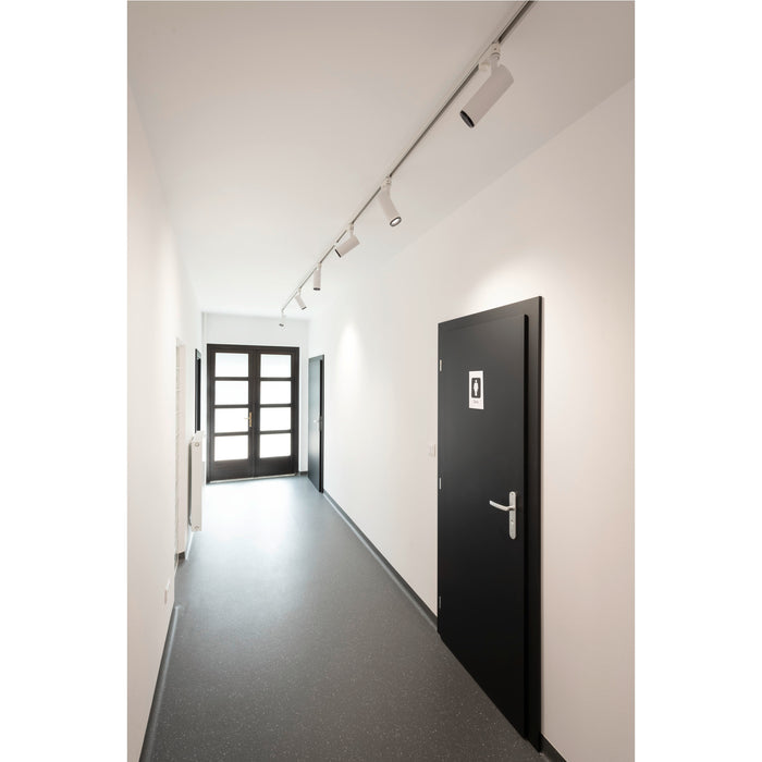 Hallway with gray speckled flooring, white walls, black doors, and white track lighting.