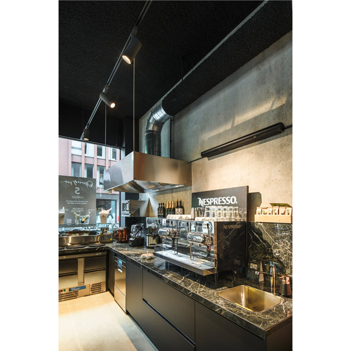 Modern kitchen with black marble countertops, stainless steel appliances, and a Nespresso machine.