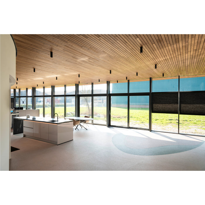 Modern kitchen with light wood ceiling, black window frames, and a white island with black countertop.