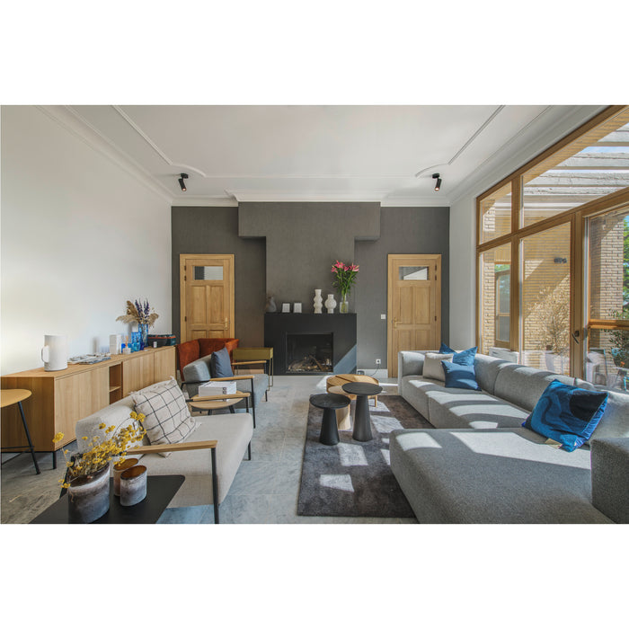 Modern living room with gray fabric sectional sofa, wood cabinet, black fireplace, and marble tile floor.