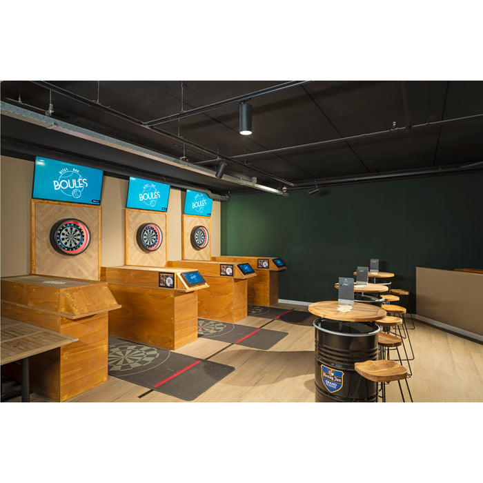 Interior of a bar with wooden dartboard stations and barrel tables with wooden stools.