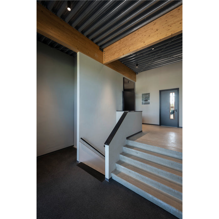 Interior with concrete stairs, wood beam ceiling, gray walls, and dark gray carpet.