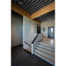 Interior with concrete stairs, wood beam ceiling, gray walls, and dark gray carpet.