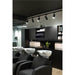 Modern hair salon interior with black cabinets, track lighting, and white ceramic shampoo bowls with black chairs.