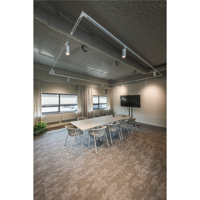 Conference room with white table, gray chairs, track lighting, and brown carpet.