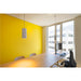 Office interior with wood conference table, black ergonomic chair, pendant lights, and yellow accent wall.