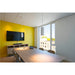 Conference room with light wood table, beige chairs, yellow wall, and white cylindrical pendant lights.