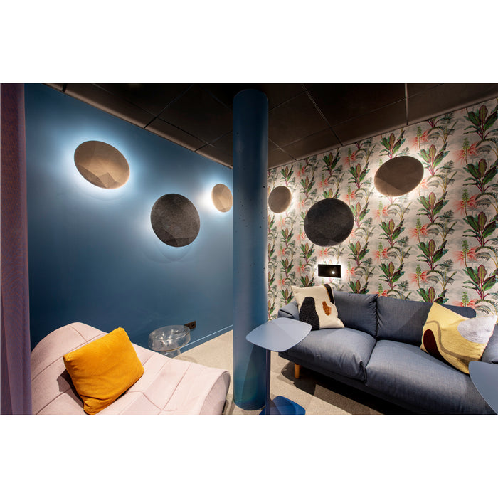 Living room with blue sofa, pink chaise, and round felt wall panels in gray and beige.