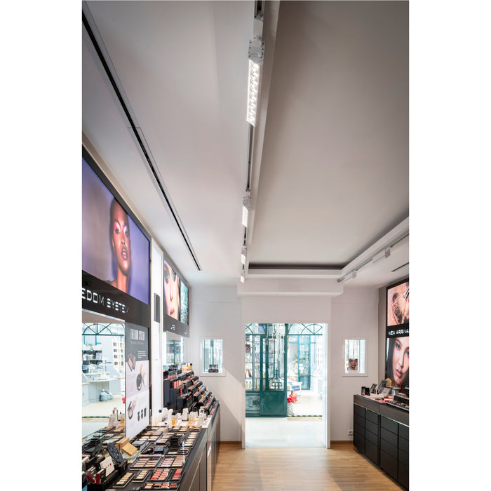Retail space interior with track lighting, makeup displays, and wood flooring.