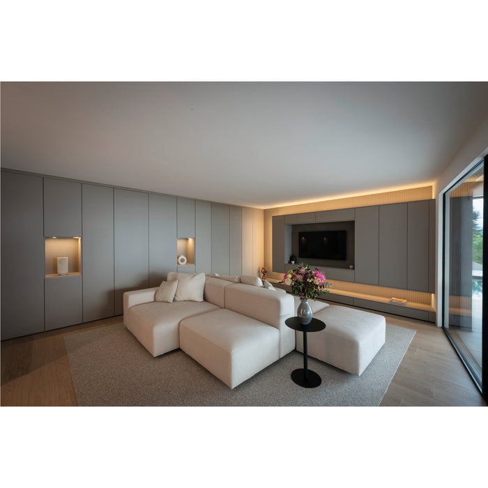 Modern living room with modular linen sofa in cream color, gray built-in cabinets, and black side table.