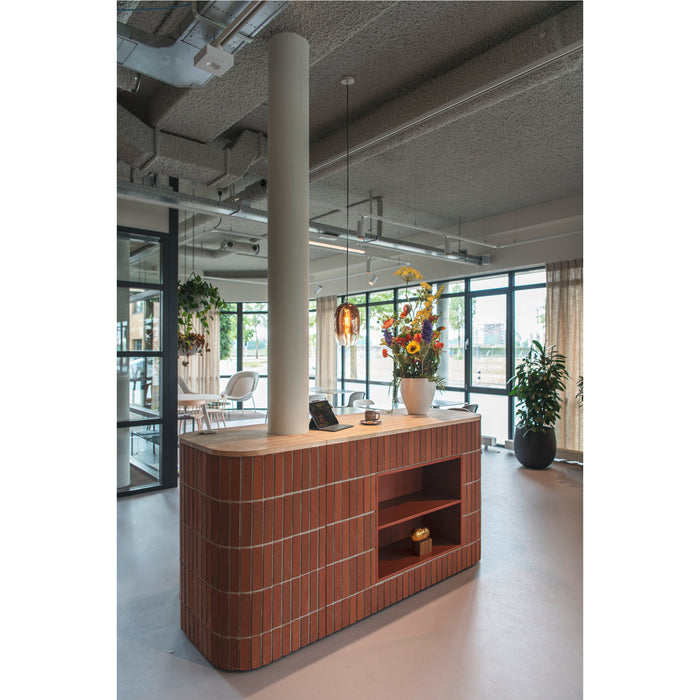 Brick reception desk with wood countertop and open shelving in a modern office space.