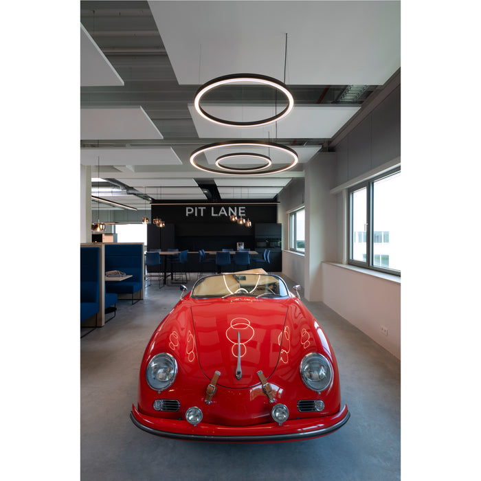 Red vintage Porsche in an office space with circular pendant lights.