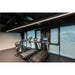 Gym interior with black treadmills and exercise bikes near window blinds.