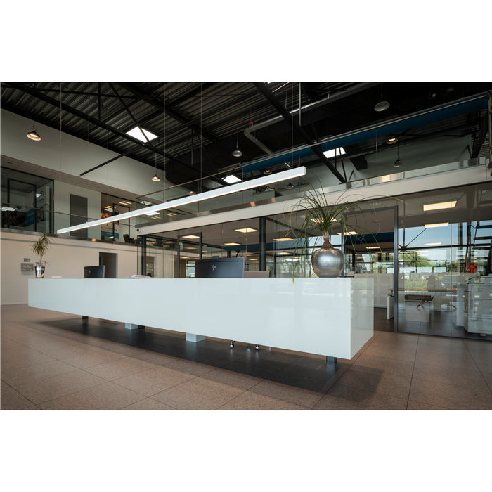 Modern office reception area with long white counter, tile floor, and glass-walled offices.