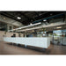 Modern office reception area with long white counter, tile floor, and glass-walled offices.