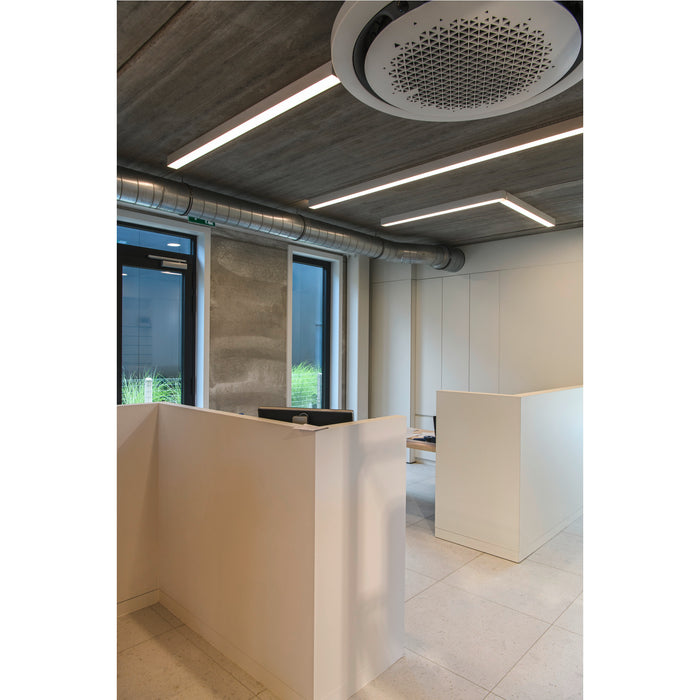 Modern office interior with concrete ceiling, linear LED lighting, white reception desk, and tiled floor.