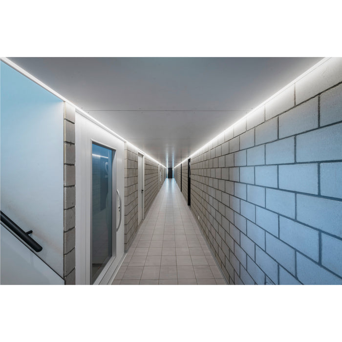 Hallway with gray concrete block walls, tile floor, and linear ceiling-mounted lighting.