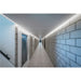 Hallway with gray concrete block walls, tile floor, and linear ceiling-mounted lighting.