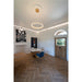 Modern interior with gold ring LED pendant light, herringbone wood floors, and blue velvet chair.