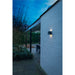 Black cube outdoor wall light, mounted on white brick.