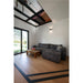 Living room with gray corduroy sofa, wood coffee table, wood floors, and black metal-framed glass ceiling.