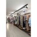 Retail store interior with clothing racks, wood shelves, and black track lighting mounted on the ceiling.