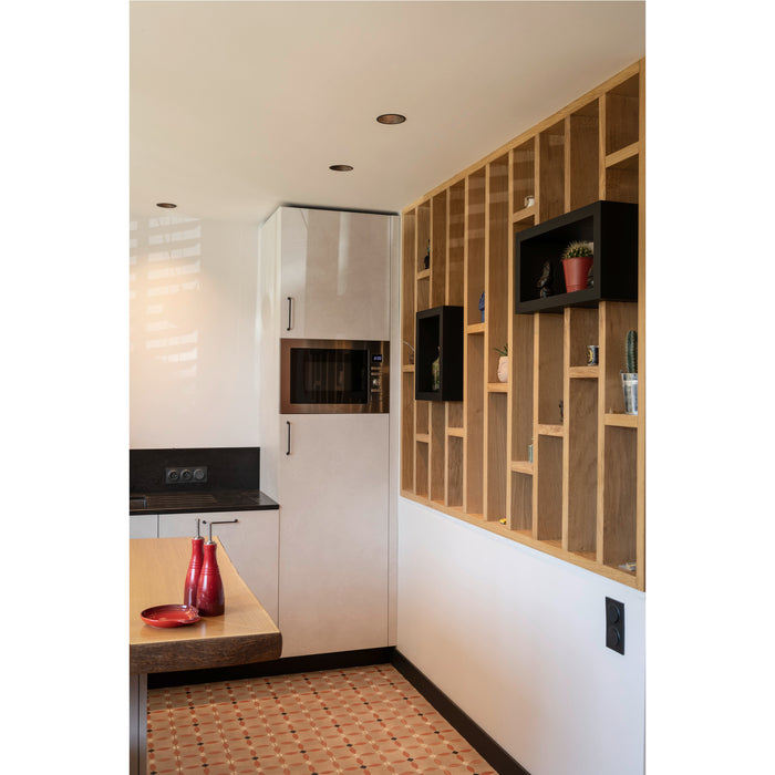 Modern kitchen with light wood shelving, black accents, patterned tile floor, and white cabinets.