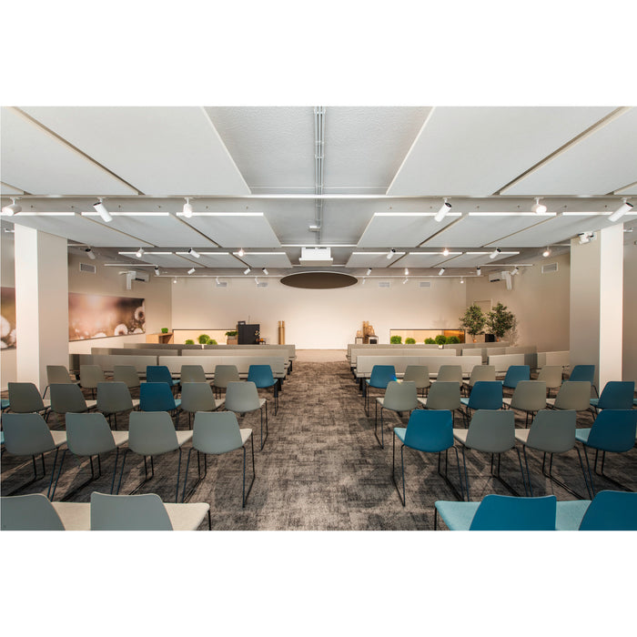 Auditorium with gray and blue upholstered chairs, gray carpet, and white ceiling panels.