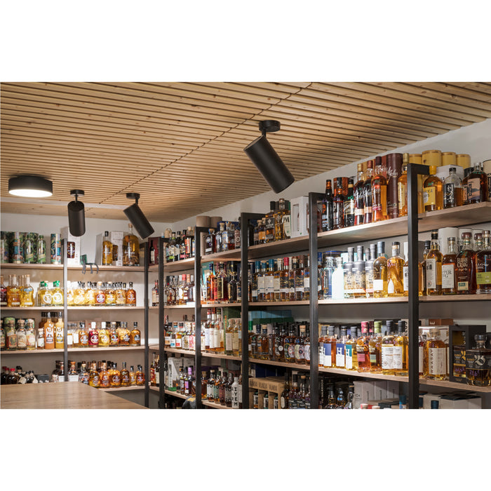 Interior view of a liquor store with shelves stocked with bottles and black, ceiling-mounted track lighting.